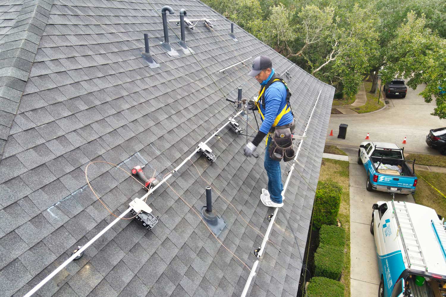 A solar installer in Houston, Texas, mounts solar panels onto a residential rooftop.