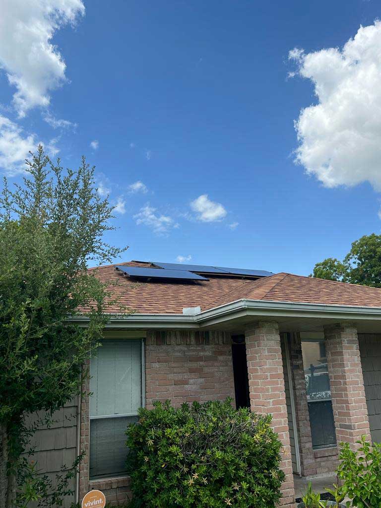 Image of a house surrounded by greenery with solar panels on the roof.